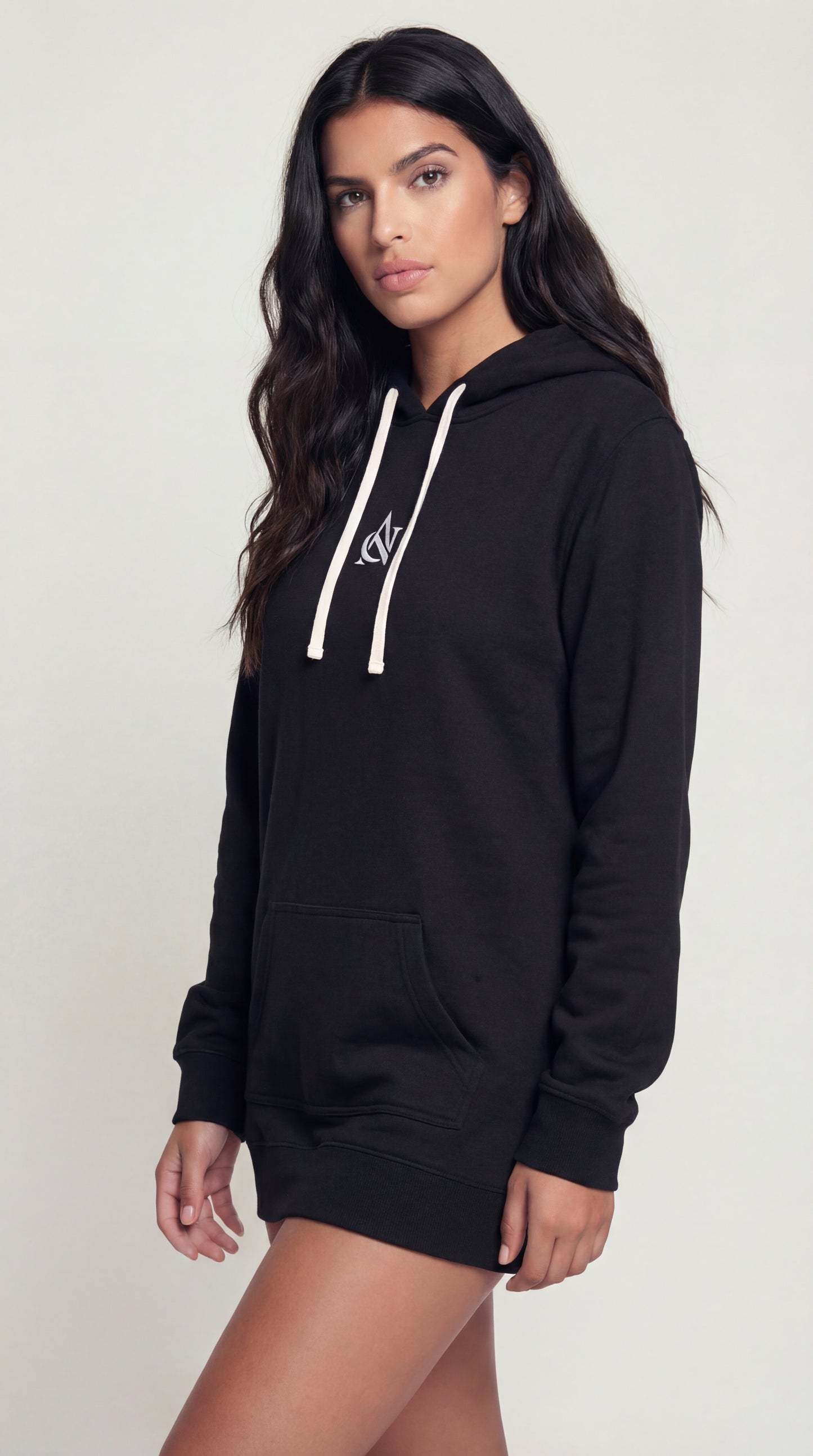 Woman wearing a black hoodie with a white logo on a plain background